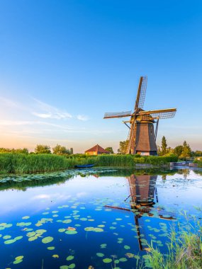 Hazerswoude-dorp, Hollanda - 22 Haziran 2020: The Rietveldse mill in Hazerswoude-dorp during the sunset. Değirmen bir hendeğin kenarında bulunuyor, bu da güzel bir yansıma sağlıyor. Günbatımı değirmeni biraz turuncu renklendiriyor.