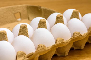 Tahta bir arka planda karton yumurta kutusundaki serbest yumurtaların yakın plan çekimi.