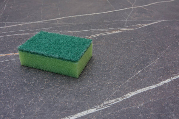 A green cleaning sponge on a marble top