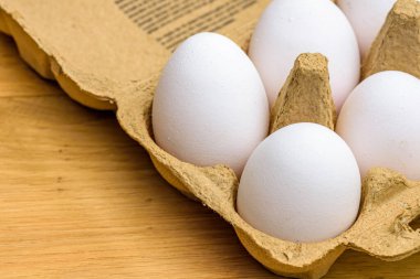Tahta bir arka planda karton yumurta kutusundaki serbest yumurtaların yakın plan çekimi.