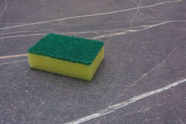A yellow cleaning sponge on a marble top