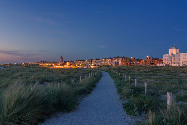 Katwijk aan Zee, The Netherlands - June 11, 2022: Sunset with the blue hour in Katwijk aan Zee with walking path from the dunes to the boulevard.