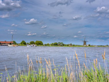 Wijde Aa manzarası. Wijde Aa, Güney Hollanda 'nın Kaag en Braassem belediyesine bağlı bir turba akarsudur. Uzakta De Wijde Aa Yelkencilik Merkezi Mill var.