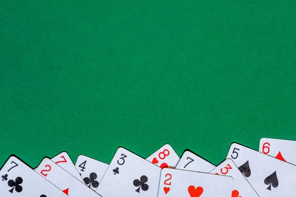Playing cards on green felt casino table. Background with copy space