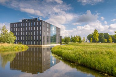 Alphen aan den Rijn, Hollanda - 16 Mayıs 2020: N11 il yolu boyunca Alphen aan den Rijn 'deki Frame Office' in ofis binası. Binanın etrafındaki gölet güzel bir yansıma sağlıyor..