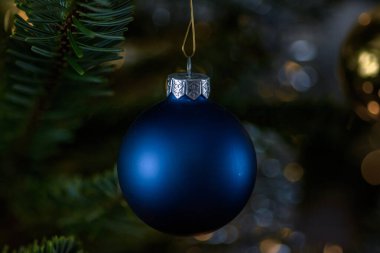 A blue Christmas ball in the Christmas tree with a dark background clipart