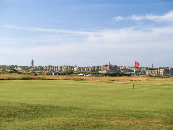 Red hole flag on golf course with urban skyline behind at St Andrews Scotland.