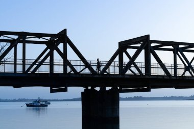 Tauranga sabahı, Tauranga Limanı 'nda maviye karşı demiryolu köprüsünün arka ışıklandırılmış görüntüsü. gökyüzü