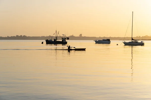 在市中心的海滨日出时 船桨在轮廓中飘过 阳光照射在水面上 — 图库照片