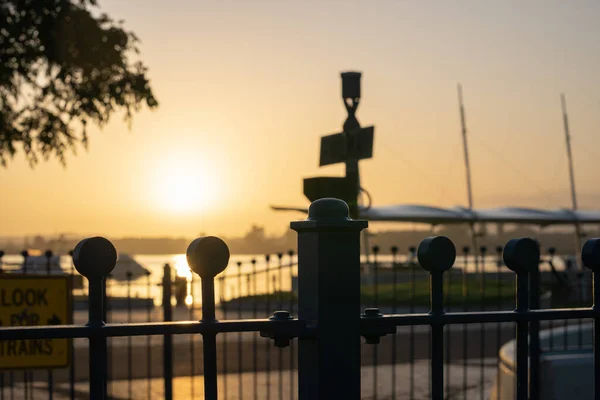 市中心滨水日出金光闪烁着倒映灯 在陶兰加滨水区设置了轮廓屏障和铁路标志 — 图库照片