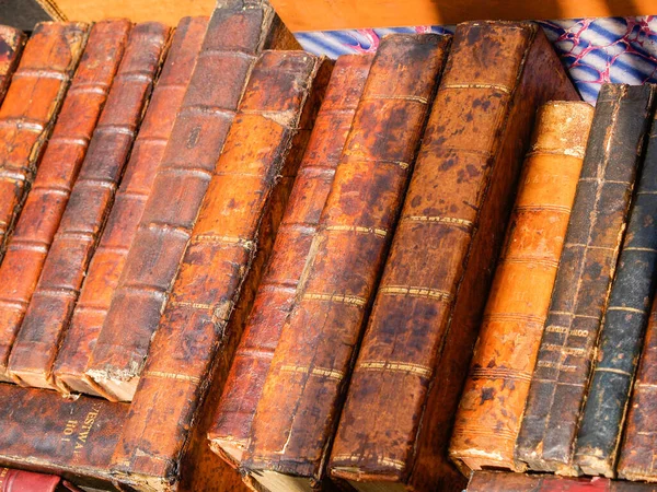 Row of vintage leather book spines without titles in market.