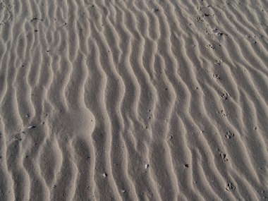 Kum desenleri sahilde dalgalanır.