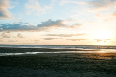 Okyanus üzerinde günbatımının uzak ufuklarında siluet içinde plaj..