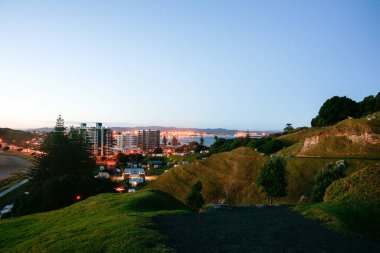 Maunganui Dağı, Tauranga Yeni Zelanda 'dan ışıklar hala açıkken gün doğarken.