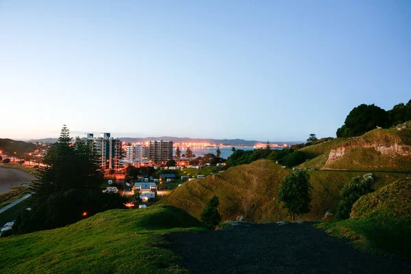 マウンガヌイ山の斜面から町の中に光がまだある間 太陽が昇ると タウランガニュージーランド — ストック写真