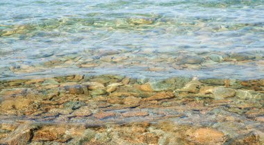Marlborough Sound, Yeni Zelanda 'da turkuaz suyla dolu taşlı plaj renkli kayalık kenarı yıkıyor..
