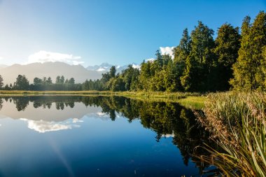 Mathieson Gölü 'ndeki yansımalar, Yeni Zelanda' nın güneyindeki doğal çalı, orman ve Güney Alpler sıradağlarıyla çevrilidir..