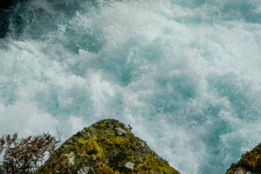 Huka Falls rapid water surging through bush clad gorge at Taupo New Zealand.