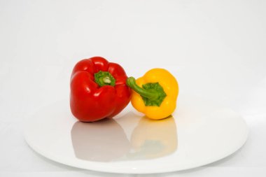 Two Capsicum fresh on white plate and background, red and yellow.