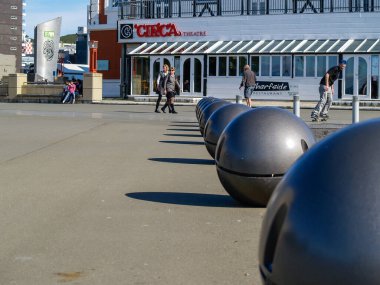 Wellington New Zealand - October 2 2010:people  walking by popular landmark Circa Theatre bar and cafe in background beyond row of Light Balls in city waterfront