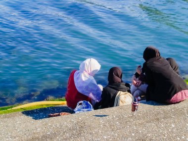Wellington New Zealand - October 2 2010;  Rear view four Muslim women in hijab sitting by bay