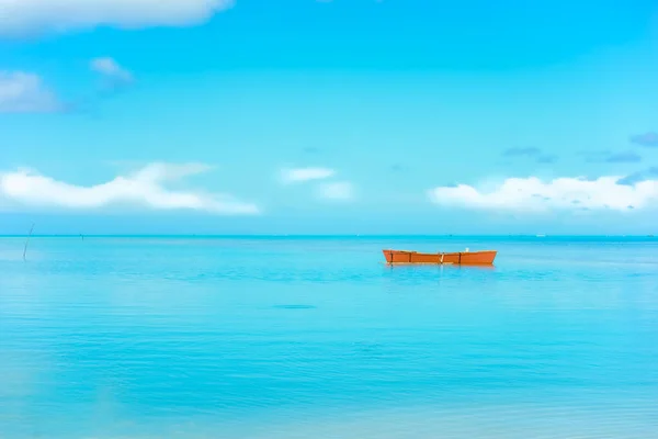 Orange color outrigger canoe on turquoise tropical water view to heat shimmer effect on distant horizon.