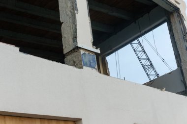 View of crane through opening in building in process of demolition in city business district