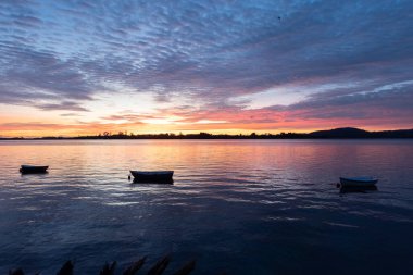 Üç küçük sandalın demirlediği körfezin üzerinde muhteşem bir gün doğumu..