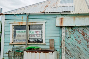Rawene Yeni Zelanda - 6 Mart 2011; Yıpranmış eski yeşil bina, camında balık ve fiyatları yazan.