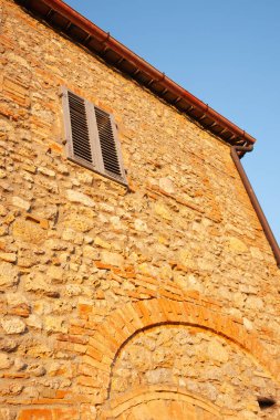 Mavi gökyüzünün altında taş duvarla örülmüş alçak bir perspektif.