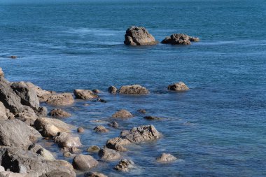 Üsteki Maunganui Dağı, Yeni Zelanda çevresinde mavi deniz bulunan Rocky sahili..