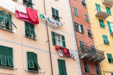 Renkli duvarlar, yeşil pencere panjurları ve tipik Akdeniz kentsel manzarasında dış apartman duvarındaki kurutma çamaşırları..