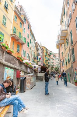 Riomaggiore İtalya - 24 Nisan 2011; Turistler ve yüksek apartman duvarları ile tipik dar şehir caddesi boyunca görünüm.