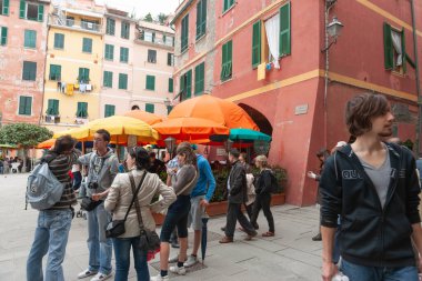 Vernazza İtalya - 24 Nisan 2011; İtalya Cinque Terre 'deki popüler turizm merkezi Piazza Marconi' de tipik patik binalarla çevrili turist ve şemsiyelerle dolu