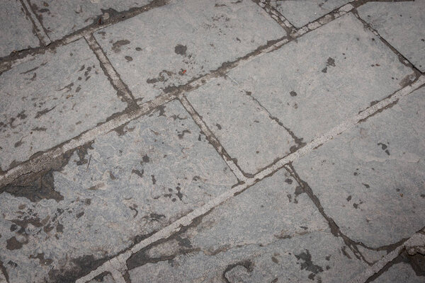Typical pattern of concrete cobblestone path weathered and worn from use.
