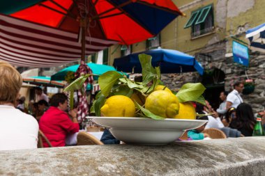 Monterosso İtalya - 25 Nisan 2011; Arka planda Bokeh 'de şemsiye altında restoranları olan açık hava restoran duvarındaki beyaz limon kasesine odaklanın.