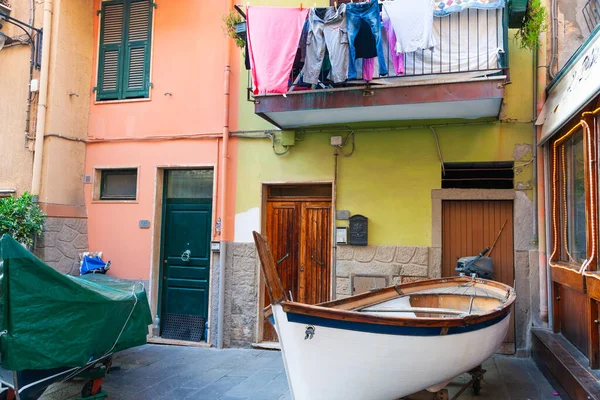 Manarola İtalya - 25 Nisan 2011; Sokağın sonundaki evlerin giriş kapıları klasik Akdeniz balıkçı teknesi yanaştı ve balkon korkuluklarının üzerine çamaşır yıkadı