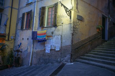 Riomaggiore İtalya - 26 Nisan 2011; Geniş adımlar ve Cinque Terre 'de sokak lambaları ve otel tabelası olan binalar arasında.