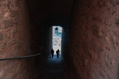 Uzakta, Portovenere 'de uzun taş duvarlı tünelde tanınmayan iki kişi..