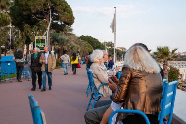 Cannes France - 30 Nisan 2011; Walkway on Boulevard de la Croisette Öğleden sonra geç saatlerde Made in Cannes tabelasının yanından geçen insanlarla.