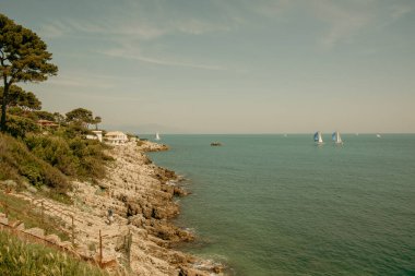 Antibes 'te, Fransız Rivierası' nda kayalık kıyılarda yelken açan yatlar..