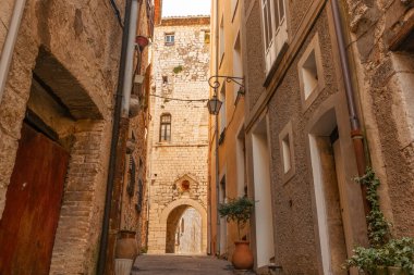 Yerleşim bölgesindeki gölgeli yüksek duvarlı eski Avrupa yolunun sonundaki duvarda güneş parlıyor. Saint Paul de Vence, Provence, Fransa.