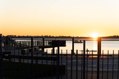 Tauranga 'nın arka planında, Strand rıhtımının üzerinde altın parıltılı arka plan ışıklandırmasıyla gün doğuyor.