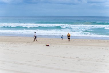 Sörfçüler Cenneti - 25 Eylül 2023; İnsan deniz kıyısını metal dedektörüyle tararken insan ve oğlu sörften uzaklaşıyor.