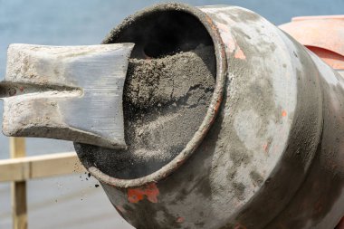 Focus on grit and sand inside concrete mixer turning blurred in motion as sand leaves raised  shovel clipart