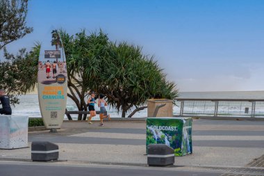 Sörfçüler Paradise Australia; 23 Eylül 2023; Sörf tahtası, sabah sporu için koşucuların şafakta yola çıktıkları Esplanade 'de yerel bir anketi destekliyor.