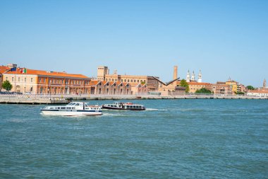 Venice İtalya - 10 Mayıs 2011; Sanayi ufuk çizgisinin arka planına karşı liman boyunca insan taşıyan küçük yolcu botları.