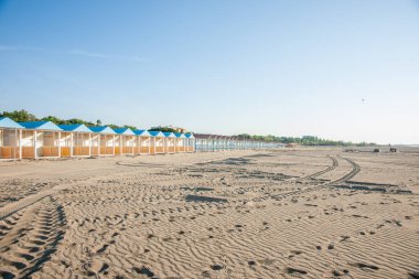 Lido beach long row beach sheds on wide beach in morning light in Italy