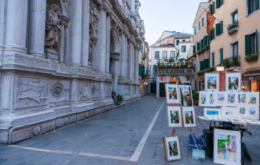 Venice Italy - May 10 2011; Art on display in traditional city street with shop at end.