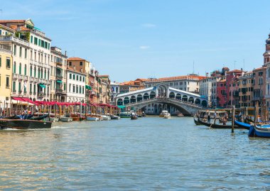Venice Italy - May 10 2011; Boats along and sailing on Brand Canal with Rialto Bridge and surrounding Venetian buildings.